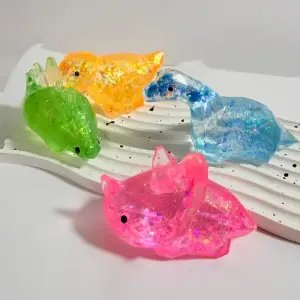 Vier glitzernde Dinosaurier-Figuren in Orange, Grün, Blau und Pink auf weißem Ständer