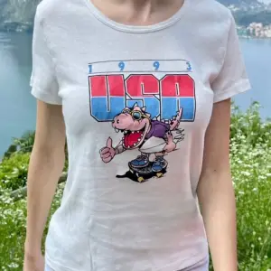 Weißes Damen-T-Shirt mit rosa Dinosaurier auf Skateboard, im Freien getragen