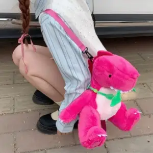 Pinker Plüsch-Dinosaurier als Rucksack, von einer Person getragen