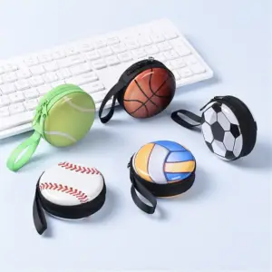 Mehrere runde Münzbörsen mit Ballmotiven und Handschlaufe auf einer Tastatur