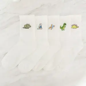 Weiße Socken mit kleinen gestickten Dinosaurier-Motiven auf Marmor