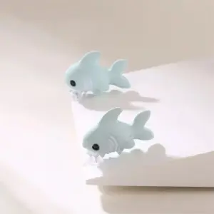 Hellblaue Hai-Ohrstecker in Tierform, die ins Ohrläppchen beißen