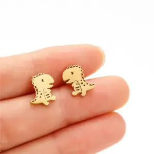 Goldene Ohrstecker in Dinosaurierform auf zwei Fingern gehalten